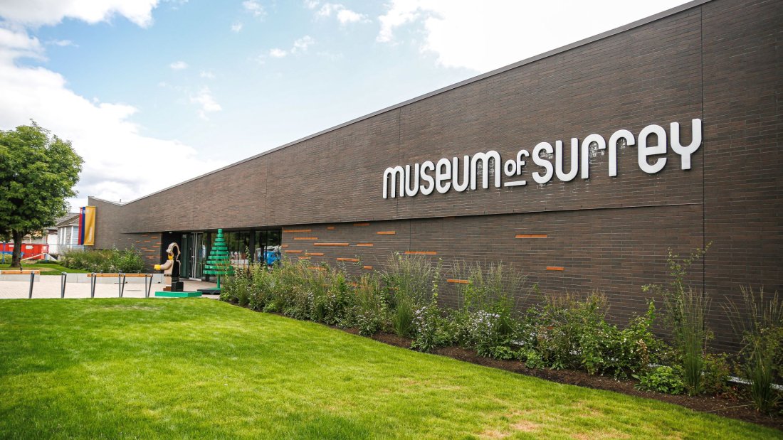Exterior brick wall of Museum of Surrey with blue sky and green grass