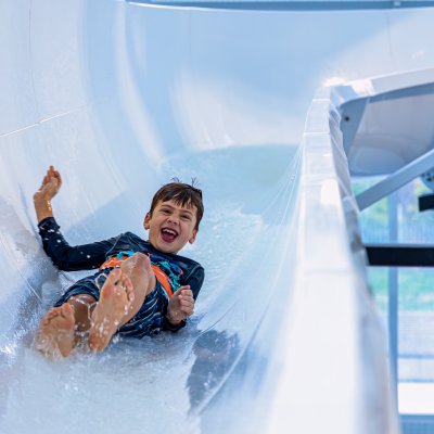 A child sliding down a slide at a pool.