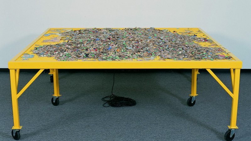 Yellow table with piles of jigsaw puzzles. 