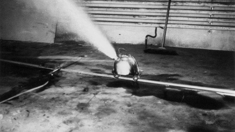 Black and white image of a kettle with a jet of steam in an abandoned warehouse.