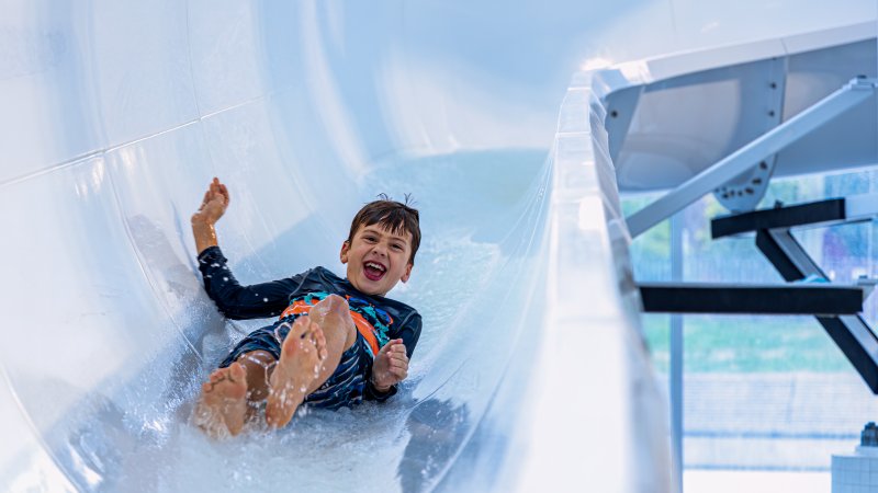 A child sliding down a slide at a pool.