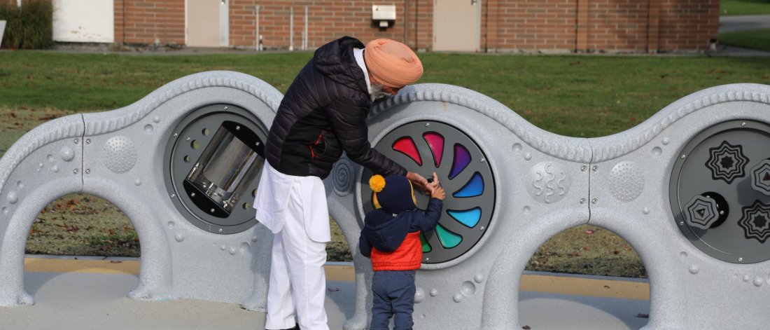 Older adult playing with a young child at Unwin Park's fully accessible playground.