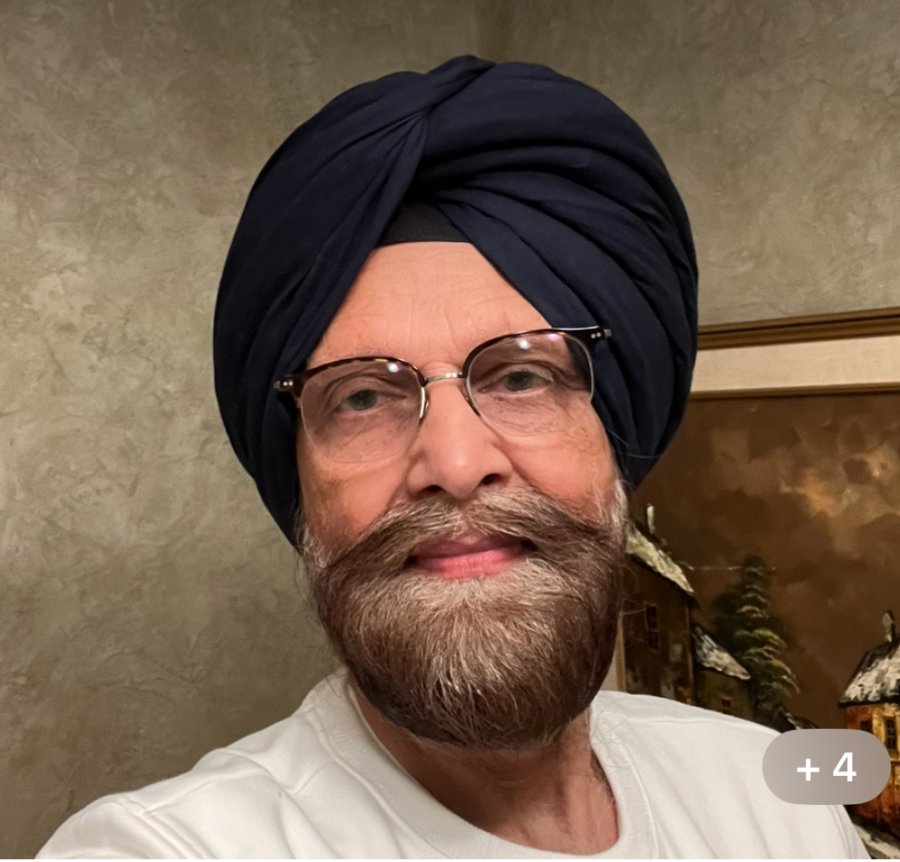  The image features an individual with a turban and glasses, smiling at the camera.