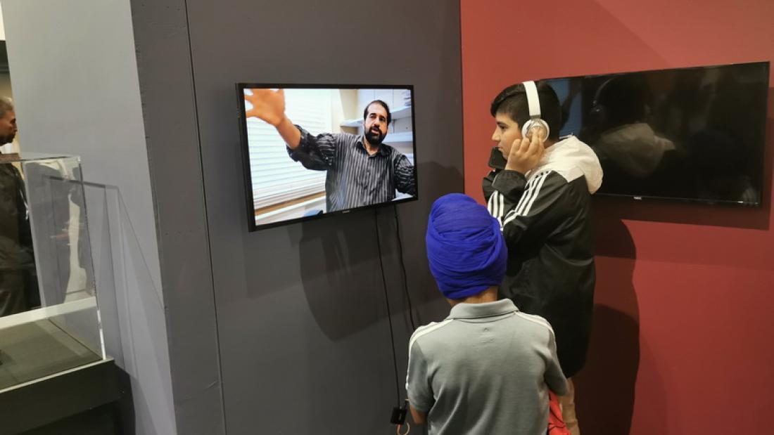 Being Punjabi Exhibit, 2 patrons watching a video