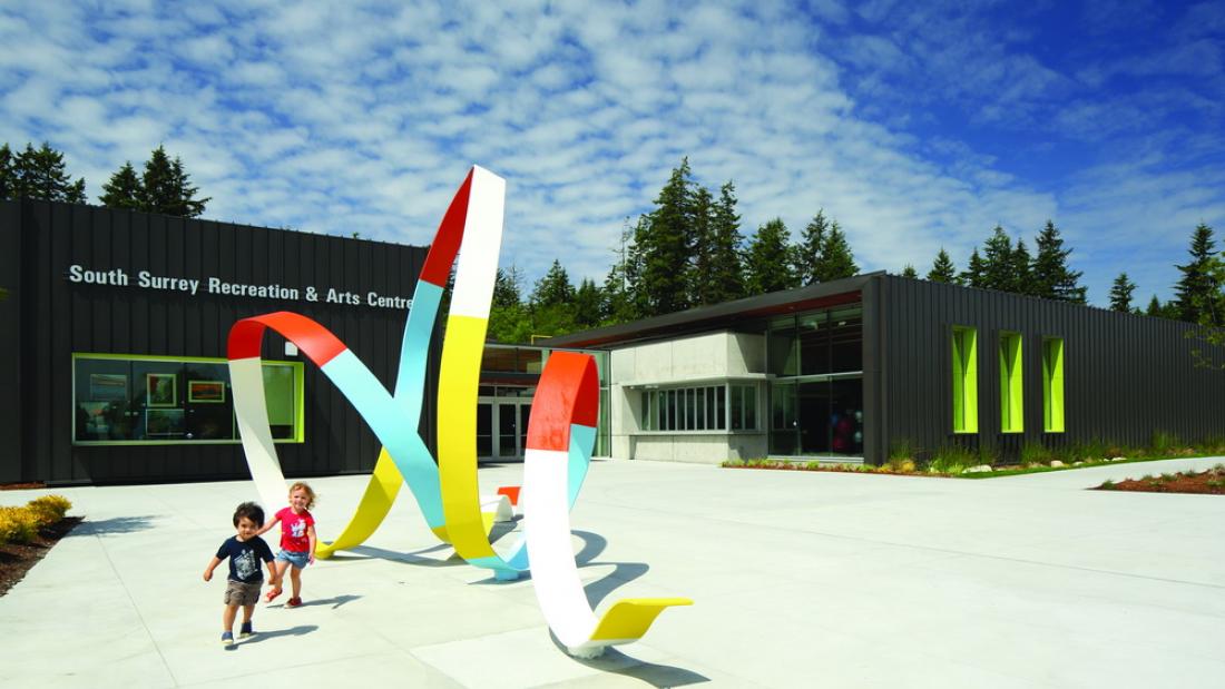Two kids near a colourful public art sculpture outdoors