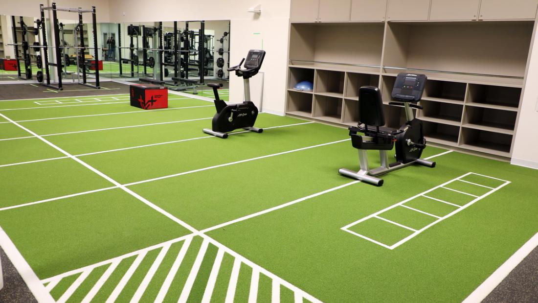 Two stationary bikes on a green turf indoors