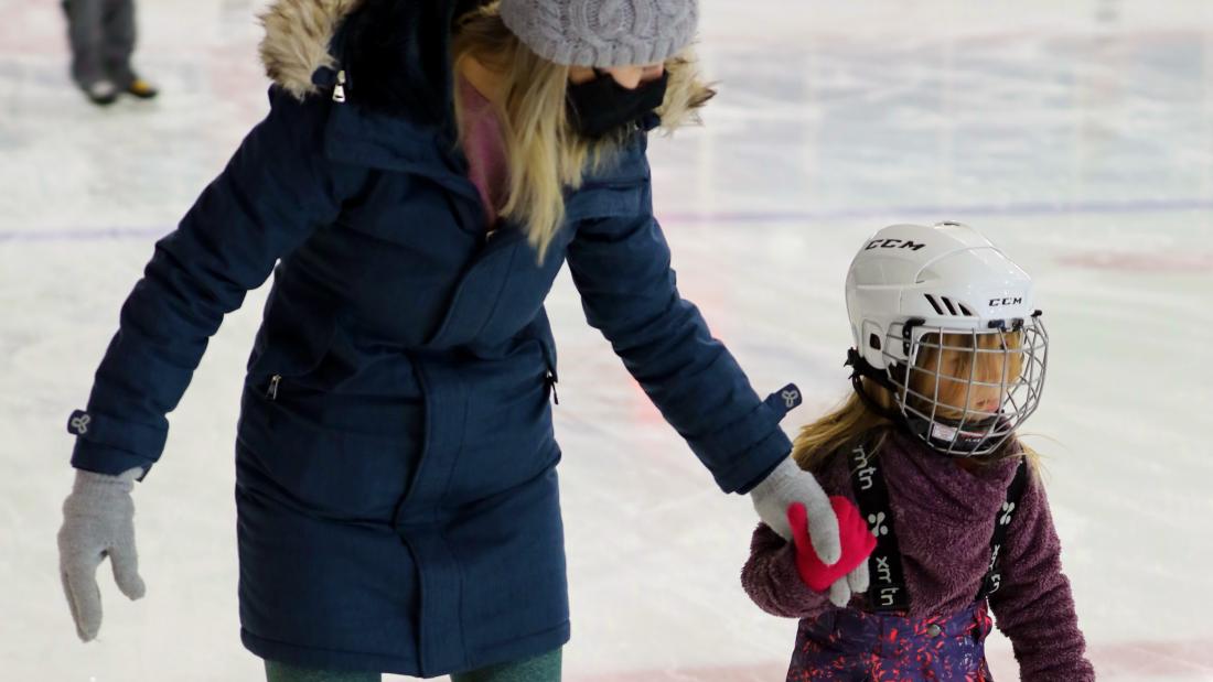 A mother and her child skating at the arena.