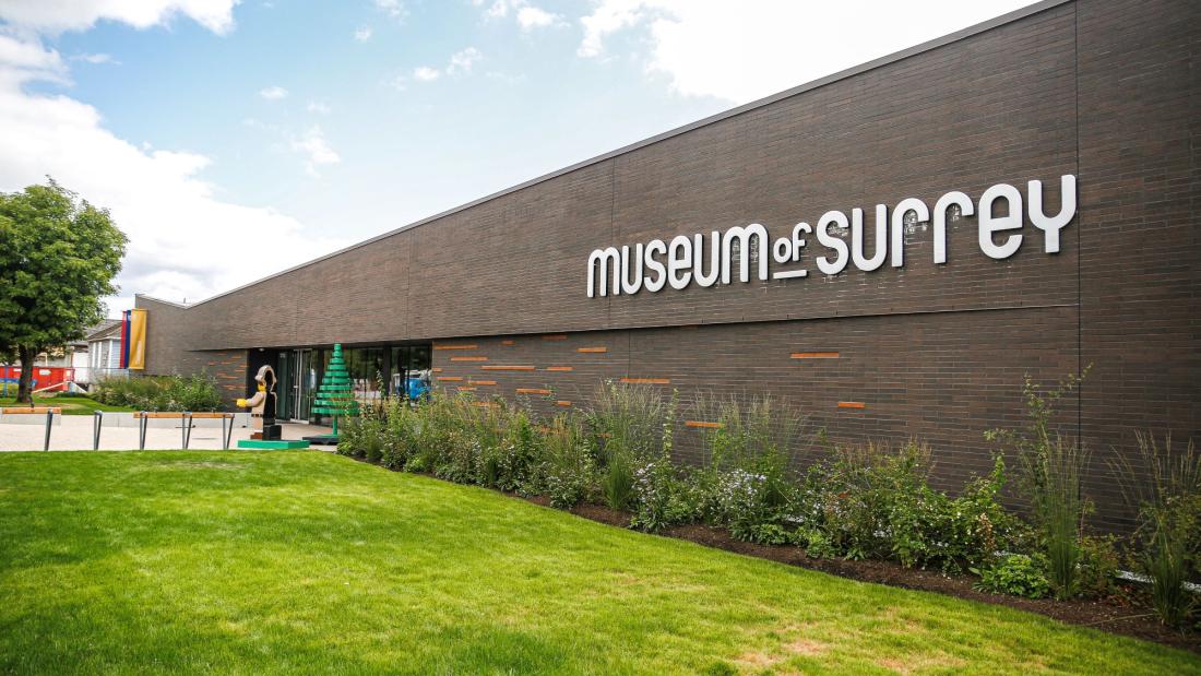 Exterior brick wall of Museum of Surrey with blue sky and green grass
