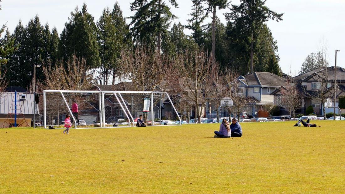 Park visitors sit on a grass field