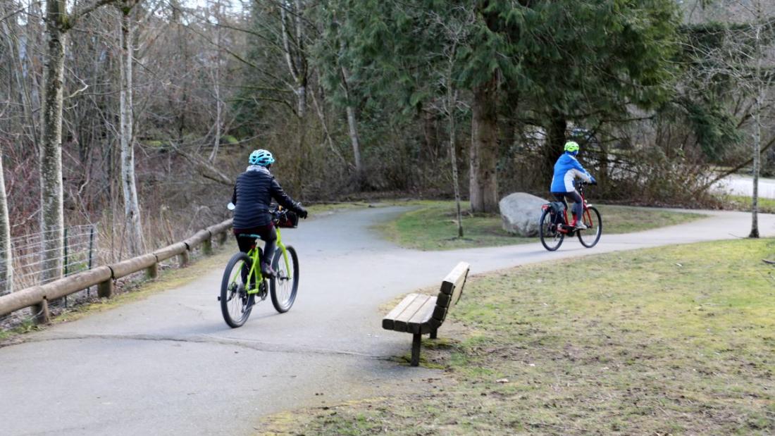 Two bikers on a paved park path in winter