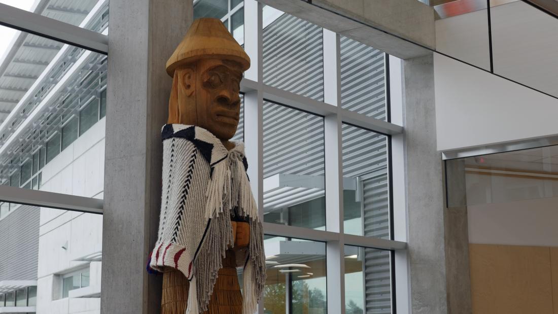 Large Welcome Pole figure made of wood with blanket around shoulders