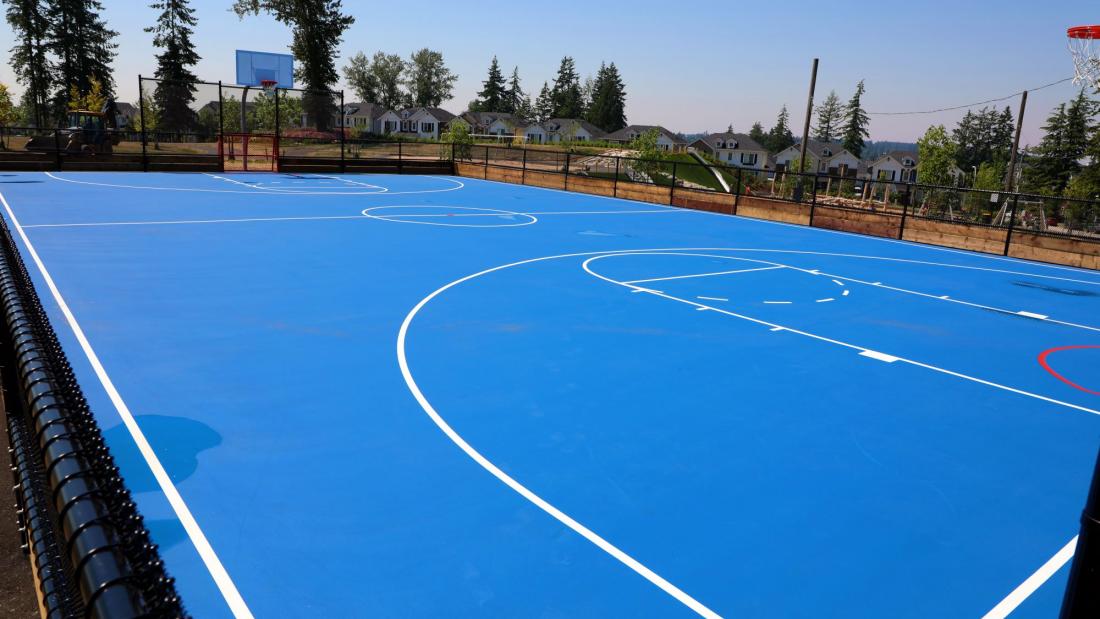 A bright blue basketball court outdoors