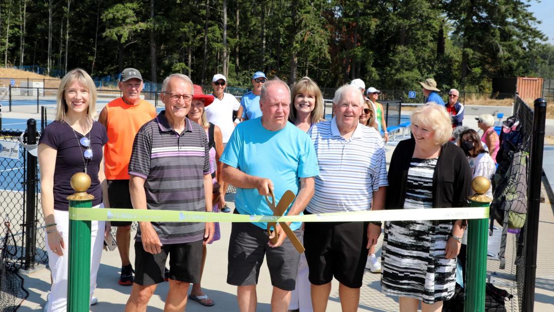 Mayor McCallum and others stand for a ribbon cutting ceremony outdoors