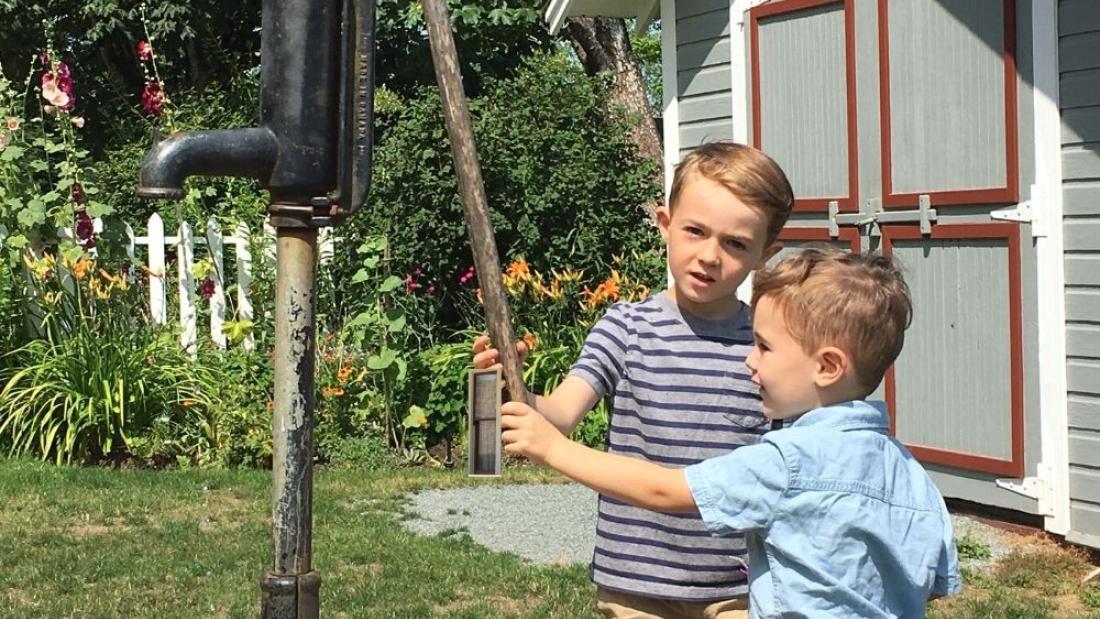 Two boys pumping water at the pump