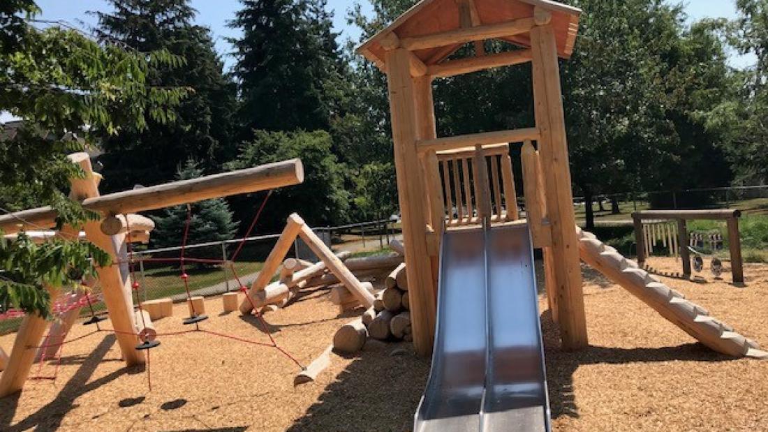 Wooden play structures with metal slide