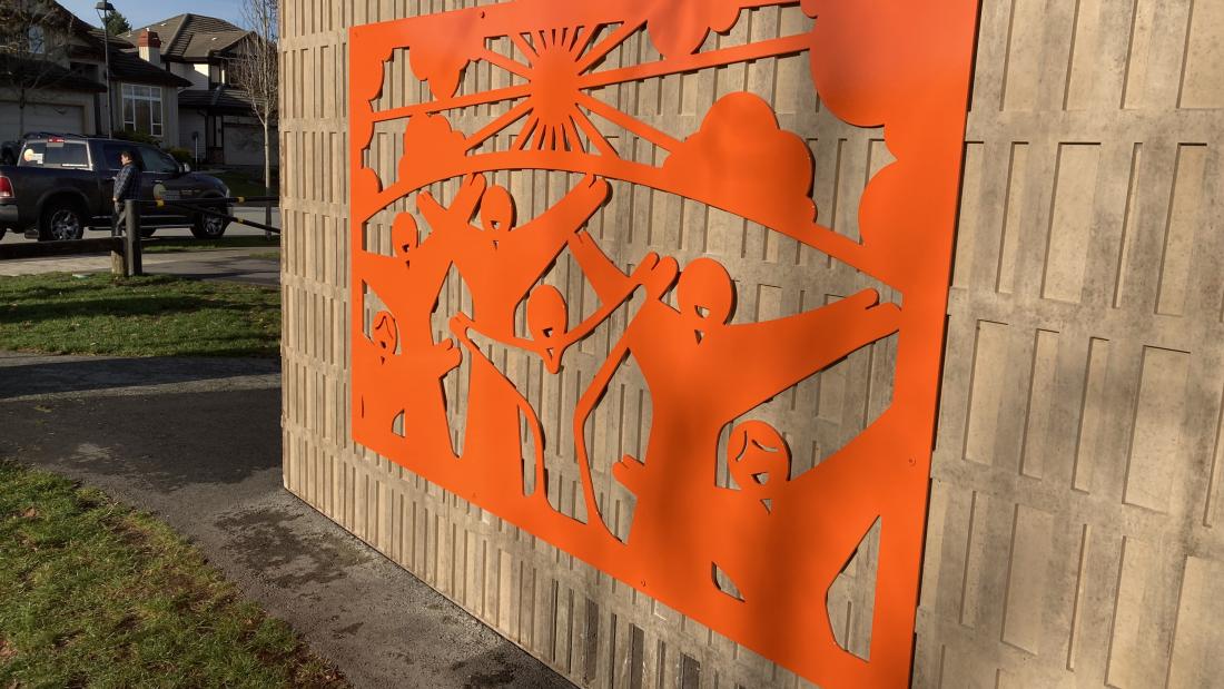 Bright orange artwork on the outside wall of a park washroom