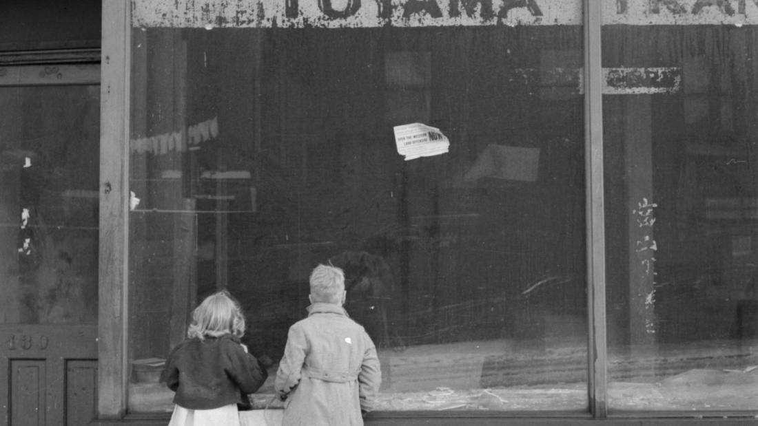 Two children look into the window of a Japanese store, closed after the forced relocation of Japanese nationals.