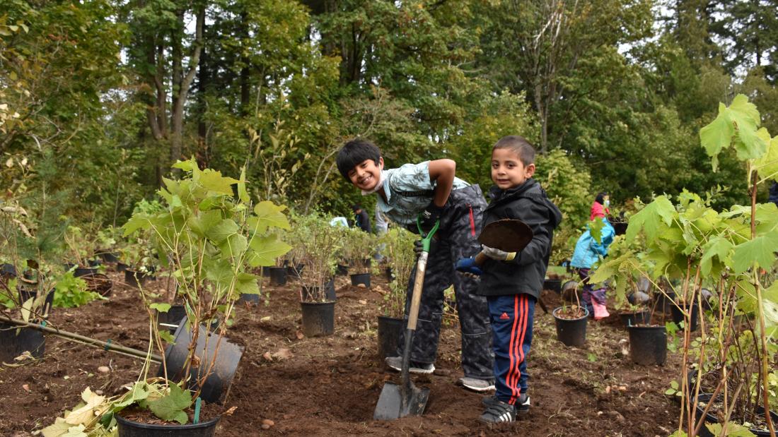 Two kids planting shrubs at Royal Kwantlen Park.
