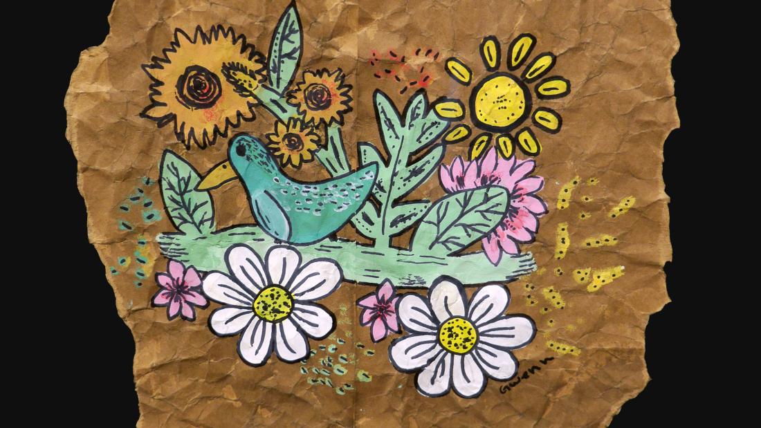 Colourful drawing of a bird among flowers on a crumpled brown paper