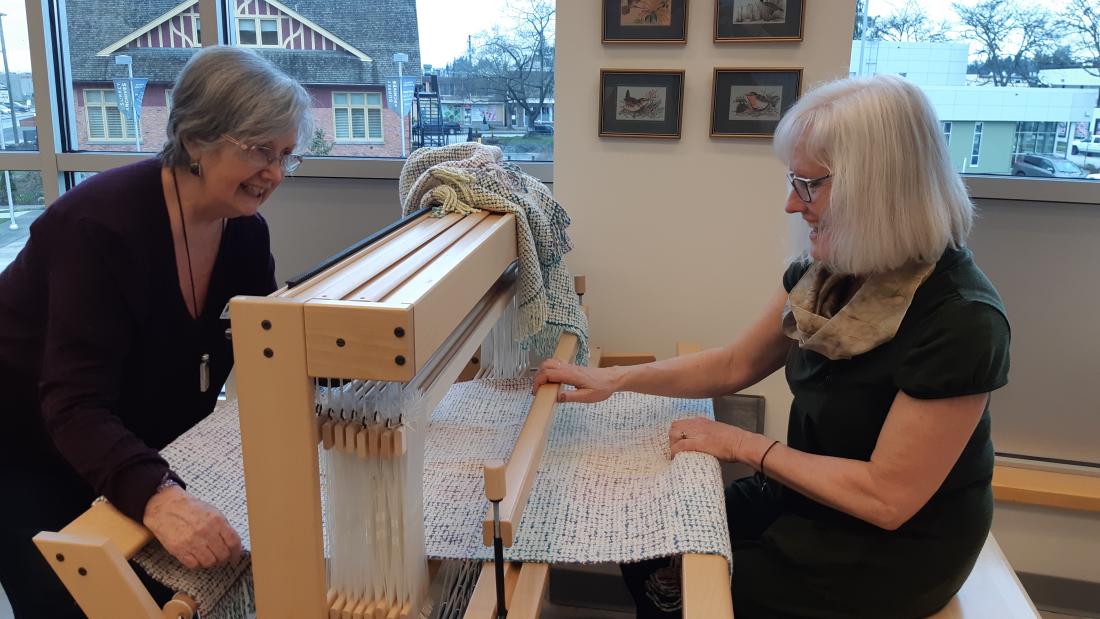 two volunteers at textile loom