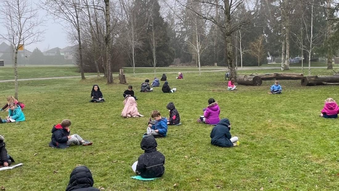 Kids sitting on the ground in a park.