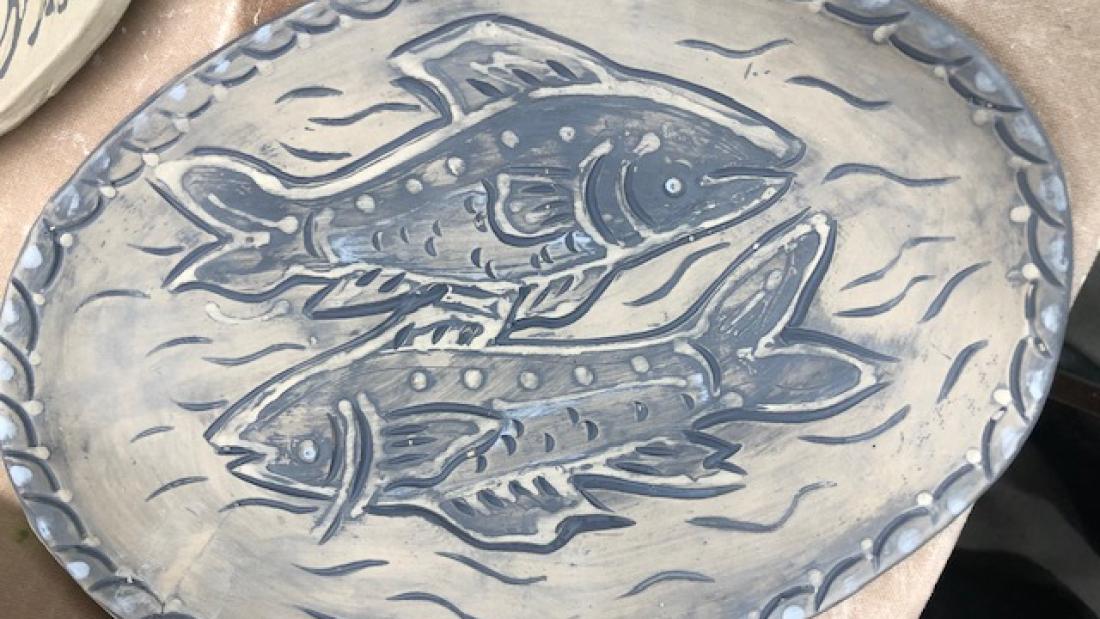 a ceramic plate with two fish on it. blue details.