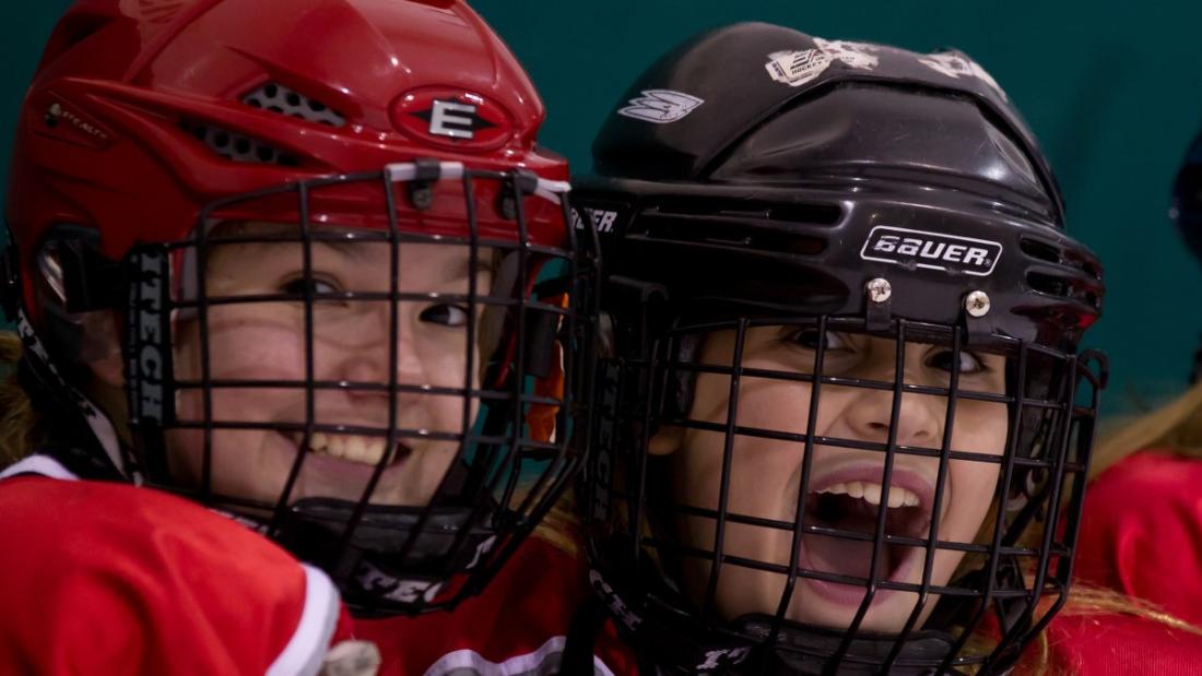 two girls in hockey helmets smiling
