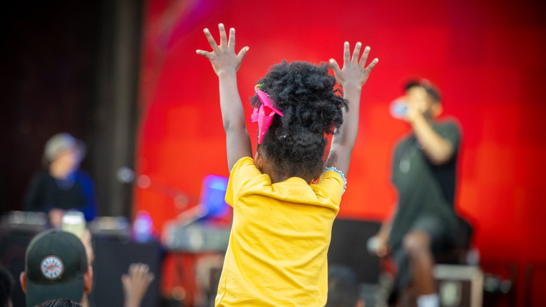 young girl with hands in the air at concert