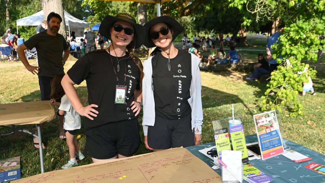 two park staff in front of a table with promotional material
