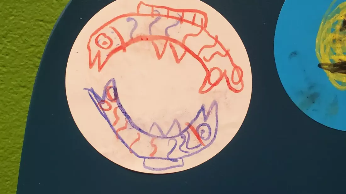 On a circular sticker is a child-like drawing of two fish.