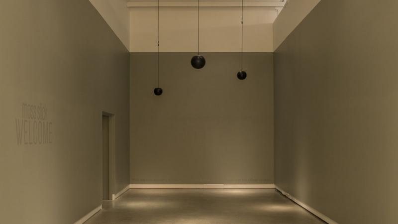 An empty room with 3 mini speakers handing from the ceiling
