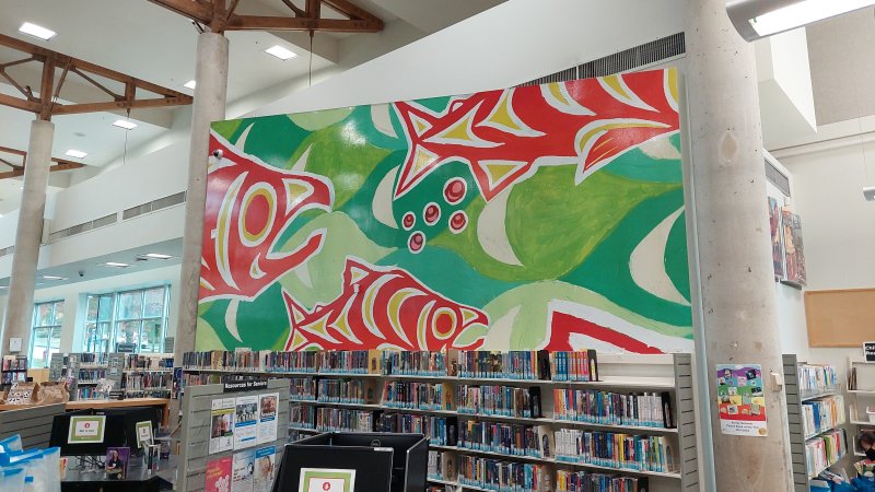 Green and red Indigenous fish mural on a library wall