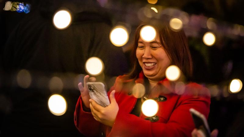 A woman on her phone enjoying the Christmas lights.