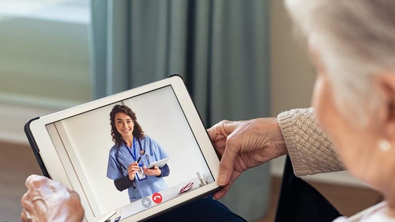 woman holding tablet, doctor appears on tablet