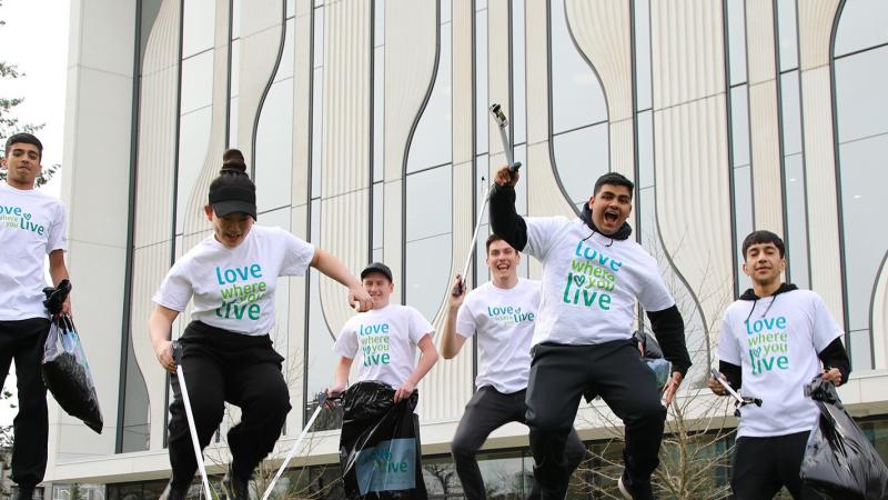 a group of youth with 'love where you live' shirts jumping in the air