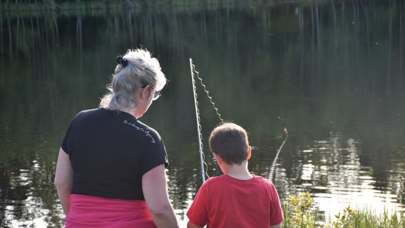 Two people fishing at a lake.