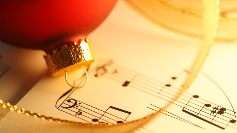 A Christmas decoration on sheet music with a ribbon