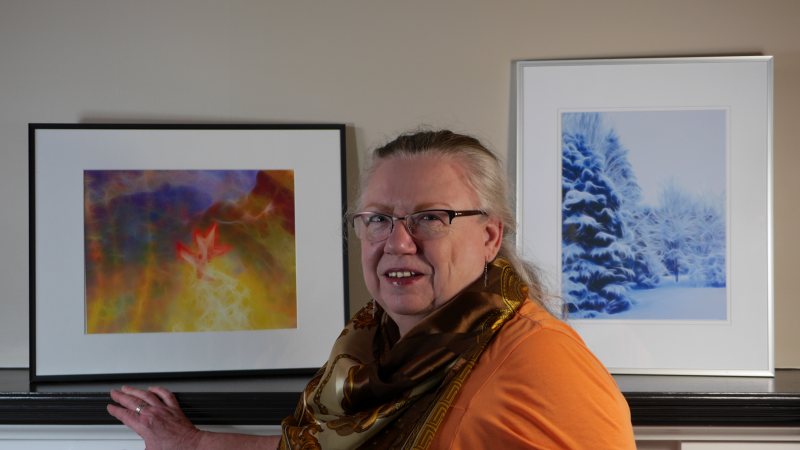Artist Leah Murray standing in front of two of her digital artworks.