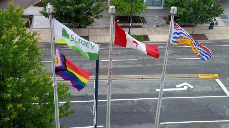 Pride flag, City of Surrey flag, Canada flag, and British Columbia flag