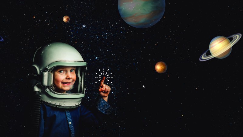 a child wearing an astronaut helmet stands in front of a back starry sky with planets in the background 
