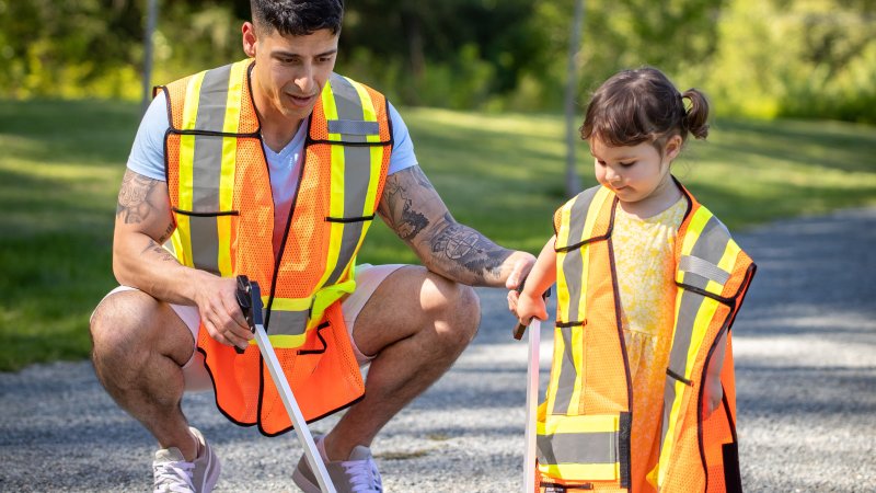 Father and daughter with high visibility vests picking up litter