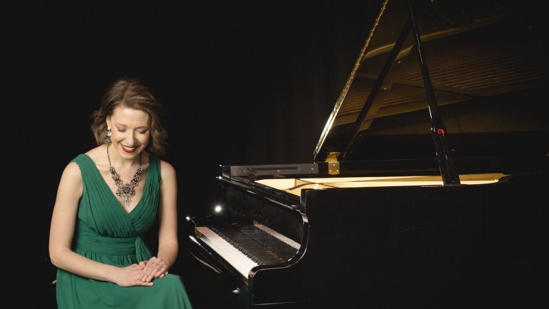 Sarah Hagen in a green dress besides a black grand piano