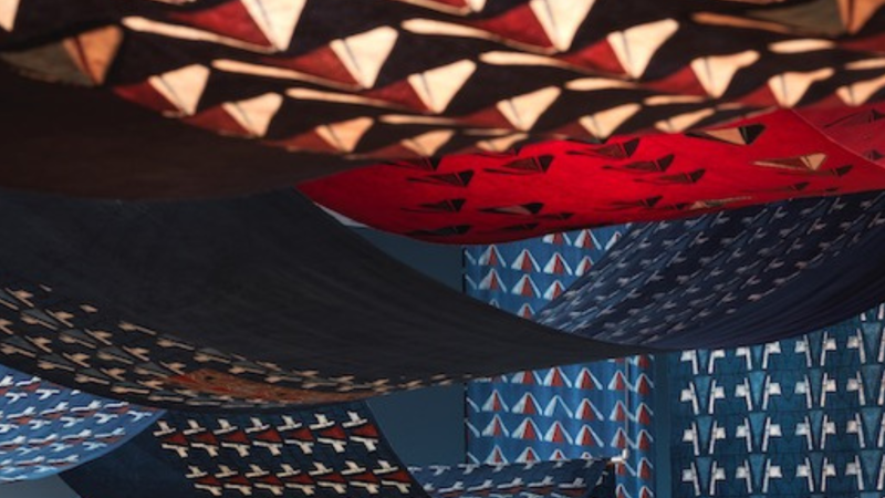 Red and blue cotton fabric with geometric patterns create a tent-like shape. 