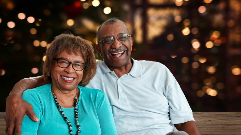 an older black male and female couple in front of holiday lights