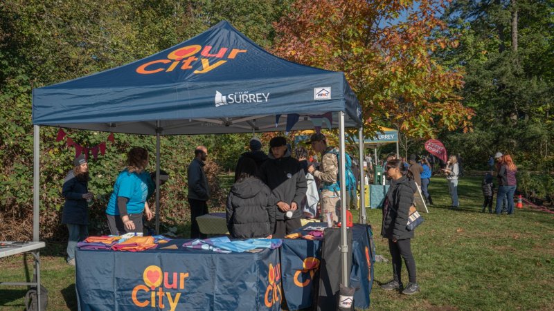  People at a table and tent with Our City branding
