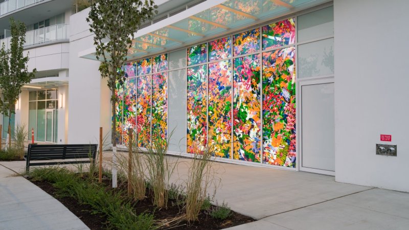  A brightly lit floral art installation on an urban building window.