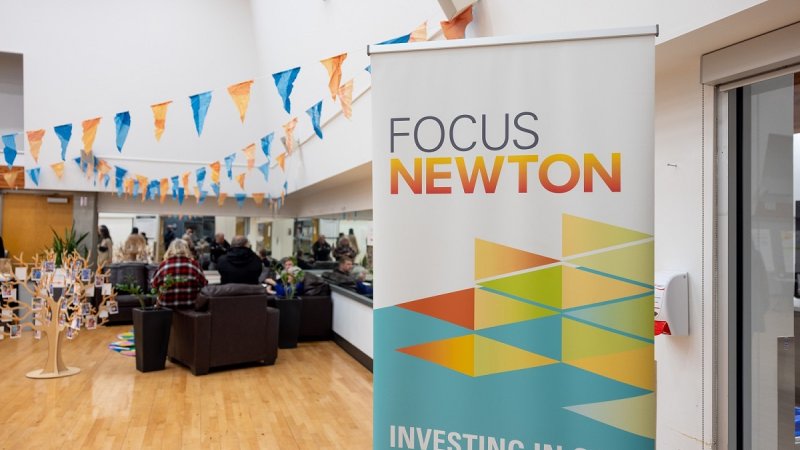  A community center with people, a "FOCUS NEWTON" banner, and colorful pennant bunting.