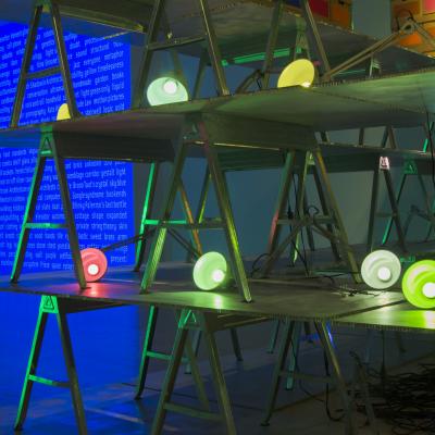 Art installation of flourescent lights sitting on top of stacked sawhorses.