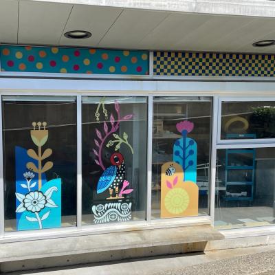 Colourful vinyl mural showing flowers and birds on window exteriors of Surrey Arts Centre classrooms.