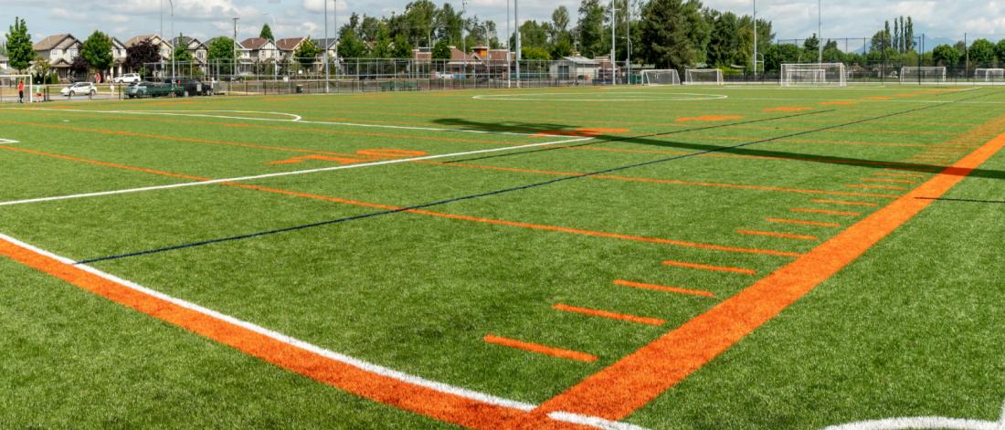 Closeup of a green sports field with orange line markings